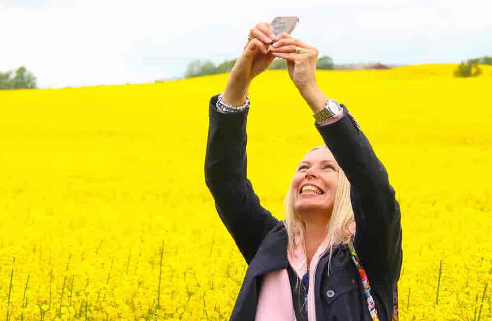 Femme se prenant en photo devant un champ de colza en fleur